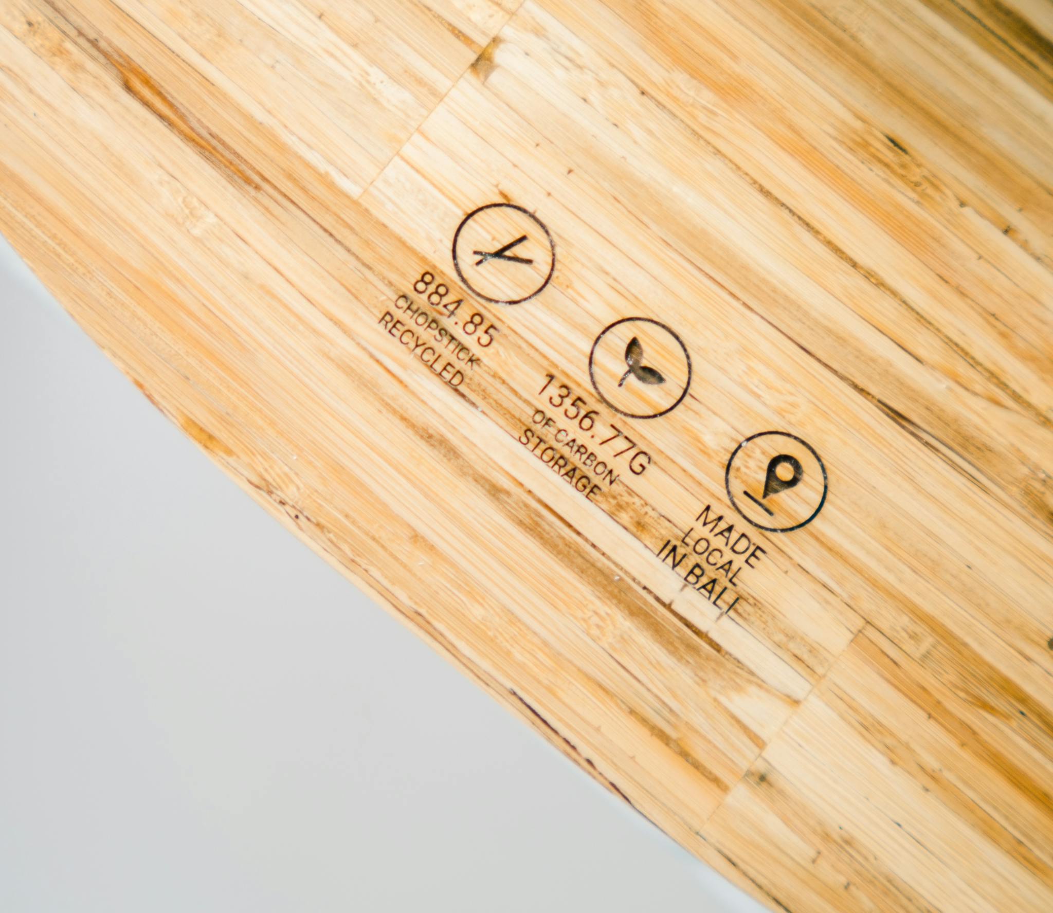 Close-up of a cutting board made from recycled chopsticks featuring eco-friendly symbols.
