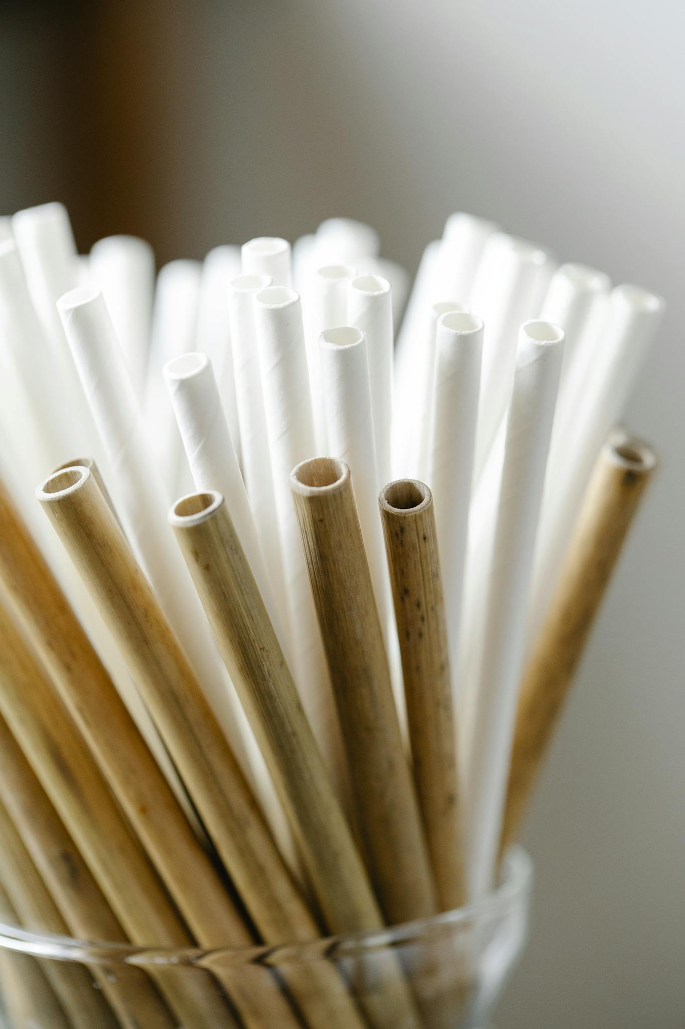 Close-up of eco-friendly bamboo and paper straws arranged in a glass container, promoting sustainable living.